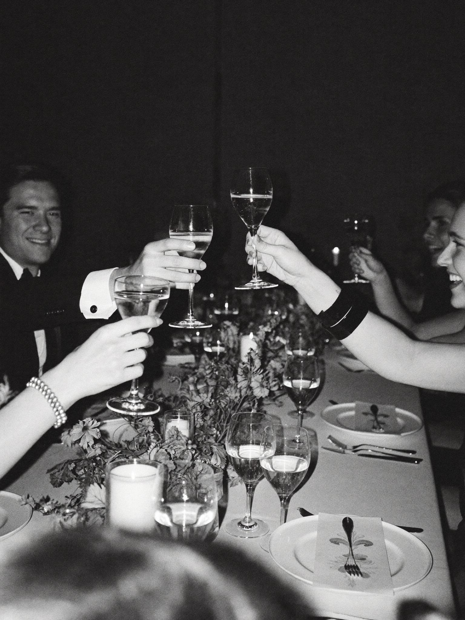 Friends raising glasses in a candlelit toast